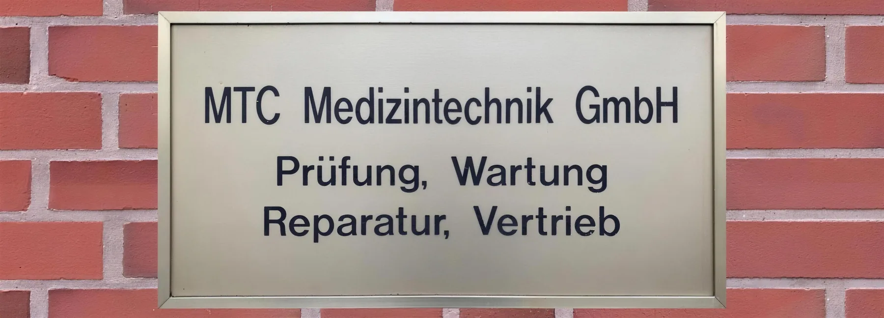 Messingschild MTC Medizintechnik GmbH an der Klinkerwand in Dorsten-Wulfen